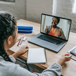 ethnic girl having video chat with teacher online on laptop